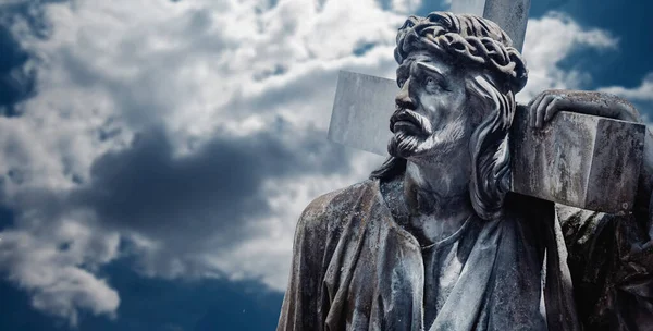 Bulutlu gökyüzünün çarpıcı manzarasına karşı haçlı antik İsa heykeli. Acı, acı ve diriliş konsepti. Boşluğu kopyala.