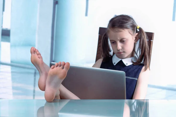 一个幽默的形象是 一个开朗的高加索女孩脱下鞋子 双脚放在桌面上 赤着脚在办公室里工作 有选择地专注于脚 图库照片