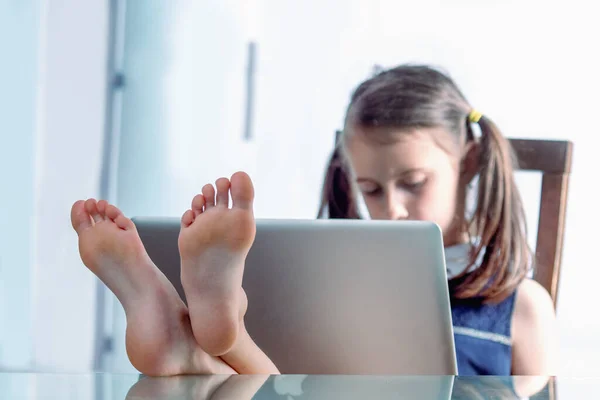 明るい白人の少女のユーモラスなイメージは 彼女の足をデスクトップに置き 素足でオフィスで働いています 足に焦点を当てて 水平像 ストック画像