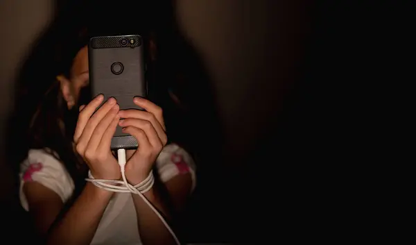 Young child girl playing smartphones during night time. She is chatting with her friend. Using phone in low light is impact to eyes. Health and gadget addiction concept. Horizontal image. Copy space.