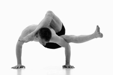 Eka pada sirsasana. Ashtanga yoga adamı spor giysisi giyiyor ve beyaz arka planda yoga egzersizi yapıyor. Siyah ve beyaz resim.
