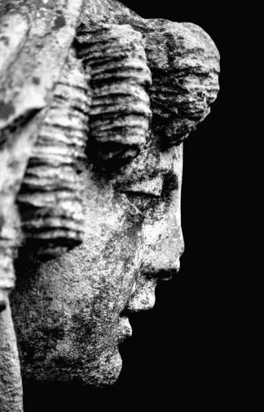 The goddess of love in Greek mythology, Aphrodite (Venus in Roman mythology) against black background. Fragment of ancient statue. Black and white vertical image.