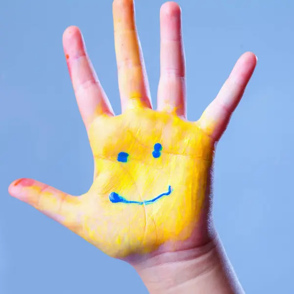 Smile as colorful painted hand as symbol of happy childhood.