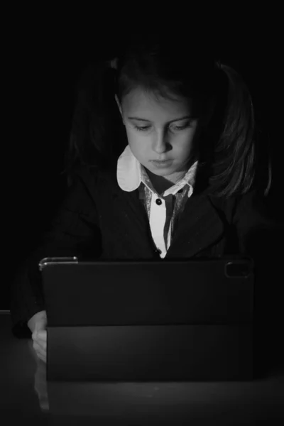 Lack of sleep as a result of studying at night may impair children\'s mood, increase stress and anxiety levels and decreased cognitive abilities. Young girl studies at night. Black and white vertical image.