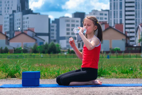 Sportif atletizm antrenmanından sonra elinde bir şişe su tutan genç kızın portresi. Spor motivasyonu konsepti. Yatay resim.