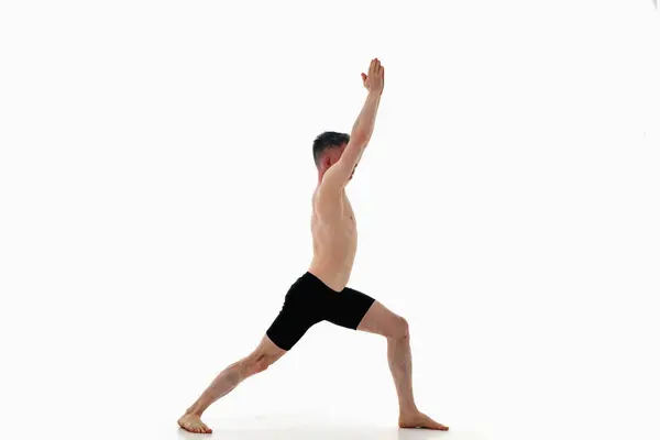 stock image Side view of man wearing sportswear doing Yoga exercise against white background. Virabhadrasana 1, Warrior 1 pose, Ashtanga yoga 