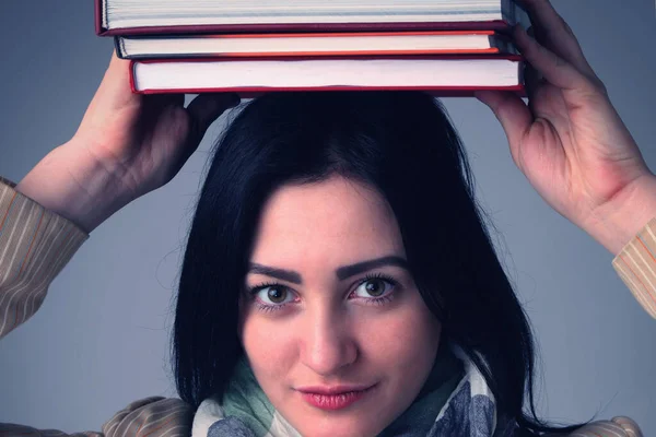 Knowledge,  self development and education concept. Portrait of young student girl balancing books on her head.