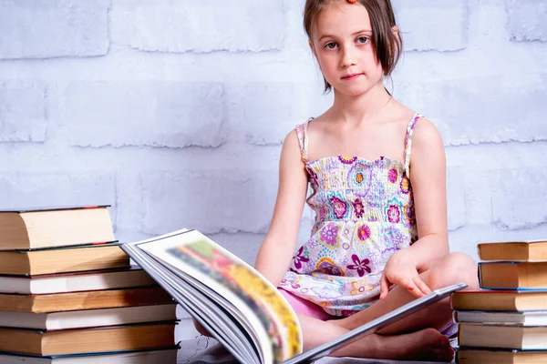 Beautiful young girl reading the book as symbol of knowledge, learning, development. Copy space.