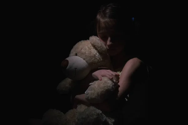 失去的童年 感情上的痛苦 孩子的痛苦 抑郁和家庭暴力 悲伤不幸的小女孩抱着她的朋友泰迪熊玩具的心理画像 免版税图库图片