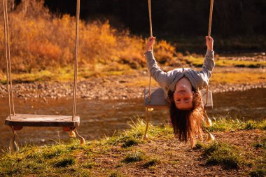Çocukların uçabilme hayalleri. Güzel genç kız salıncakta baş aşağı oturuyor. Mutlu çocukluk ve özgürlük kavramı. 