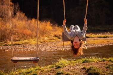 Çocukların uçabilme hayalleri. Salıncakta baş aşağı duran güzel bir genç kızın portresi. Mutlu çocukluk ve özgürlük kavramı. Yatay resim.