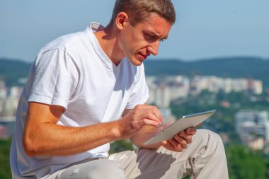 Dağın tepesinde tablet akıllı telefonla çalışan bir iş adamı..