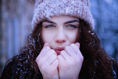 Soğuk kış günlerinde onları sıcak tutmak için ellerinde nefes alan güzel genç bir kadın. Yatay resim