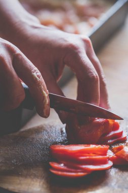 İtalyan ekmeği ve malzemeleri - parmesan, zeytinyağı, domates, baharat ve bitkiler. Şefin elleri pizzada domates dilimleri kesiyor. Lezzetli pizza hazırlığı.