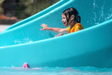 Su kaydırağından yuvarlanan mutlu genç kızın portresi. Boşluğu kopyala.