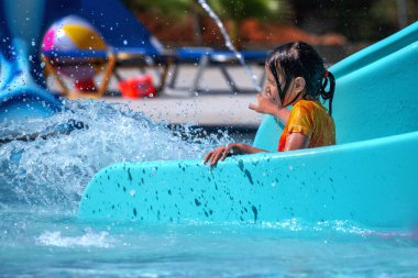 Mutlu genç kız su kaydırağından indikten sonra havuza girdi. Yatay resim.
