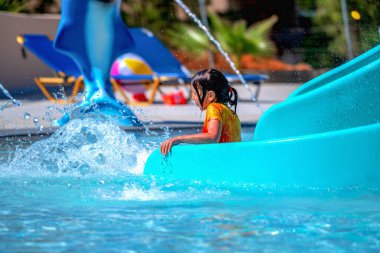 Mutlu genç kız su kaydırağına girdikten sonra havuza giriyor. 