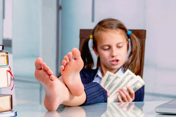 Happy young girl counts money profit. Selective focus on bare feet