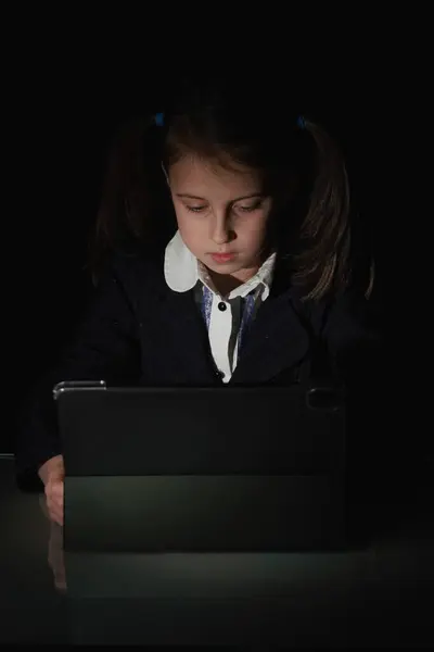 Lack of sleep as a result of studying at night may impair children's mood, increase stress and anxiety levels and decreased cognitive abilities. Young stressed girl studies online at night. Vertical image.