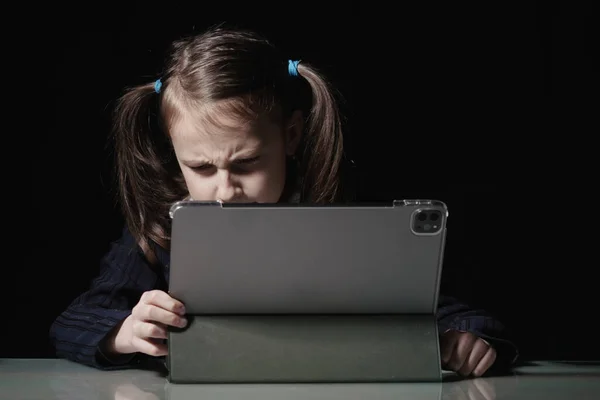 Lack of sleep as a result of studying at night may impair children's mood, increase stress and anxiety levels and decreased cognitive abilities. Young girl studies online at night. Horizontal portrait.