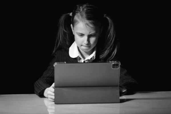 Lack of sleep as a result of studying at night may impair children's mood, increase stress and anxiety levels and decreased cognitive abilities. Young girl studies online at night. Black and white portrait.