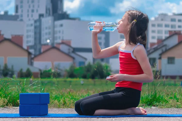 Young sporty athletic fitness girl holding bottle of water after fitness workout. Workout sport motivation concept.