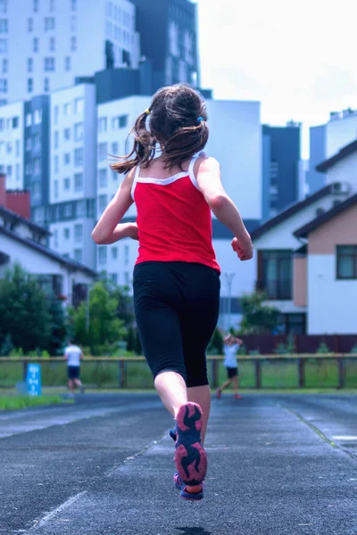 Athlete young girl in running start pose. Sport tight clothes. Vertical image.