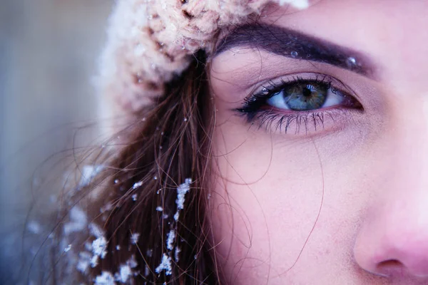 Close up portrait of young beautiful woman covered of snow. Snowflakes lie on eyelashes, eyebrows and cheeks.