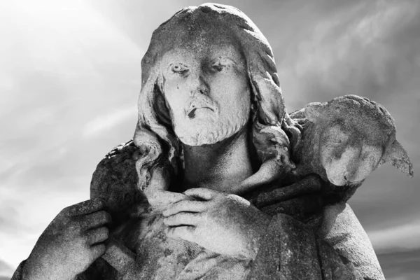 Ancient statue of Jesus Christ of Nazareth is the Good Shepherd with the lost sheep on his shoulders. Black and white image.