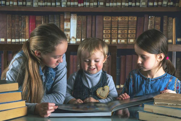 Child development and early learning. Funny image of very happy young girl studying and reading books against old books background.