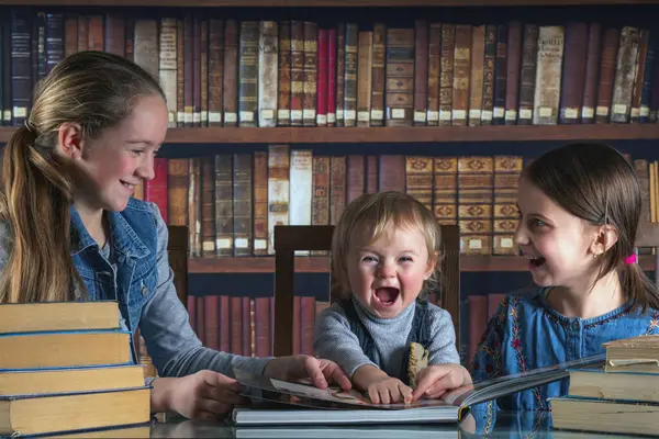 Child development and early learning. Funny image of very happy young girl studying, laughing and reading books against old books background.