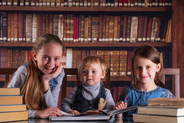 Child development and early learning. Portrait of happy young scientists studying and reading books  in the library against old books background.