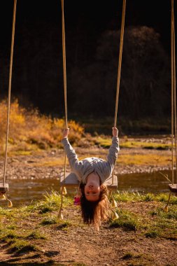 Çocukların uçabilme hayalleri. Salıncakta baş aşağı duran güzel bir genç kızın portresi. Mutlu çocukluk, özgürlük konsepti. Dikey resim.