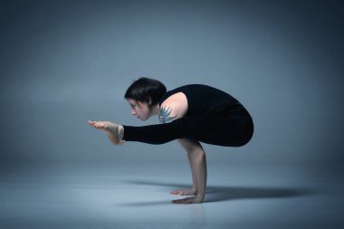 Titbhasana, Ashtanga yogası spor giysili kadın beyaz arka planda yoga yaparken görülüyor.. 