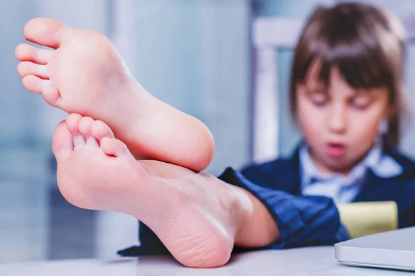 在工作和休息的同时 密切关注快乐的儿童商业女孩的肖像 对赤脚的选择性关注 免版税图库照片