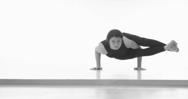Astavakrasana, Ashtanga yoga tarafı spor giysili bir kadının beyaz arka planda yoga yaparken görüntüsü. Metin veya tasarım için boşluk kopyala. Yatay siyah beyaz resim.