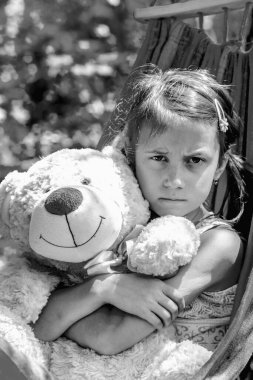Üzgün ve kızgın genç kız, oyuncak ayıya sarılıyor.