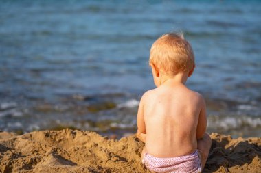 Küçük bebek sahilde kumsalda oynar yaz tatili, dinlenme, tatil, insanlar, neşe, mutluluk konsepti. Yatay görüntü. Metin veya tasarım için boşluk kopyala.