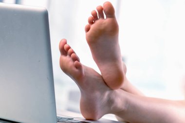 Bugün çalışmak için havamda değilim. Neşeli genç iş kızı dizüstü bilgisayarın başına çıplak ayakla geçti, ofiste çalışmak istemiyor. Yatay resim.