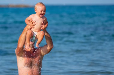 Baba portresi denizde bebekle birlikte yüzüyor. Doğa, seyahat, okyanusta oynayan mutlu baba ve çocuk. Metin veya tasarım için boşluk kopyala. Yatay resim.