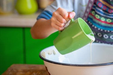 Kadın aşçı pizza hamuru hazırlıyor. Genç kız hamura süt ekler. Yemek, yemek pişirme ve el yapımı konsept sanatı. Metin veya tasarım için boşluk kopyala.