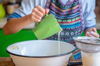 Kadın aşçı pizza hamuru hazırlıyor. Genç kız hamura süt ekler. Yemek, yemek pişirme ve el yapımı konsept sanatı. Seçici odak. 