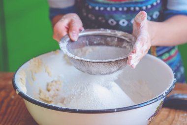 Genç bayan aşçı elleri hamur yoğuruyor, üzerine beyaz buğday unu serpiyor. Yemek, yemek pişirme ve el yapımı konsept sanatı. Yatay resim.