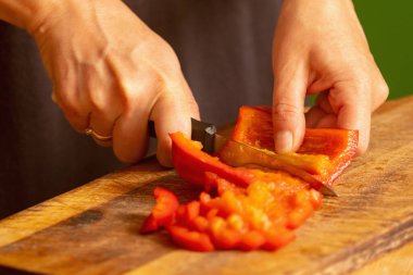 İtalyan ekmeği ve malzemeleri - parmesan, zeytinyağı, domates, baharat ve bitkiler. Şefin ellerinin portresi pizzada kırmızı biber dilimleri keser. Seçici odaklanma. Yatay resim.