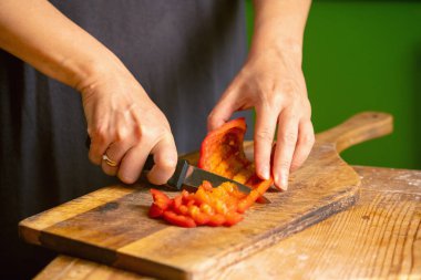 İtalyan ekmeği ve malzemeleri - parmesan, zeytinyağı, domates, baharat ve bitkiler. Şefin ellerinin portresi pizzada kırmızı biber dilimleri kesiyor..