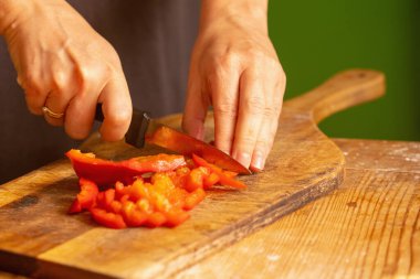 İtalyan ekmeği ve malzemeleri - parmesan, zeytinyağı, domates, baharat ve bitkiler. Şefin ellerini kapayın, pizzada kırmızı biber dilimleri kesin. Seçici odaklanma. Yatay resim.