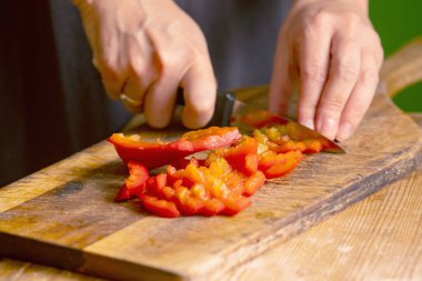İtalyan ekmeği ve malzemeleri - parmesan, zeytinyağı, domates, baharat ve bitkiler. Şefin elleri pizzada kırmızı biber dilimleri kesiyor.. 
