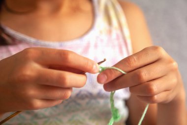 Tığ işi süreci. El ve örgü ipliği kullanan genç bir kız, el yapımı tığ işi, evde dinlenmek için hobi. Parmaklarına odaklan. Yatay resim.