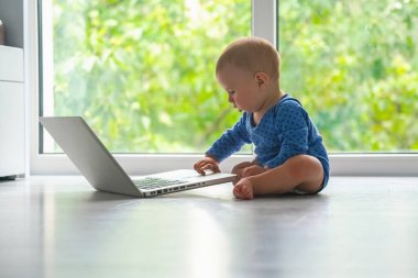 İnternetteki ilk adımlar. Küçük bebeğin komik görüntüsü dizüstü bilgisayarla çalışmaya başlıyor. Yatay resim.