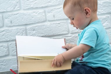 Küçük bir bebeğin portresi kitaplara bakar. Yeni doğanların entelektüel gelişimi.